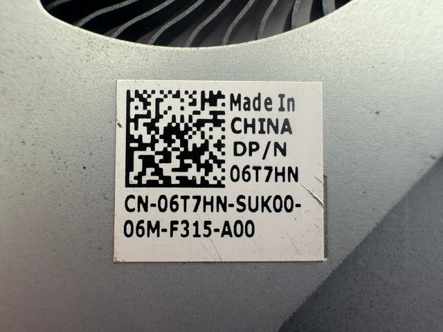 A close-up of a white product label with black text, a QR code, and 'Made in China' on a gray metallic surface.